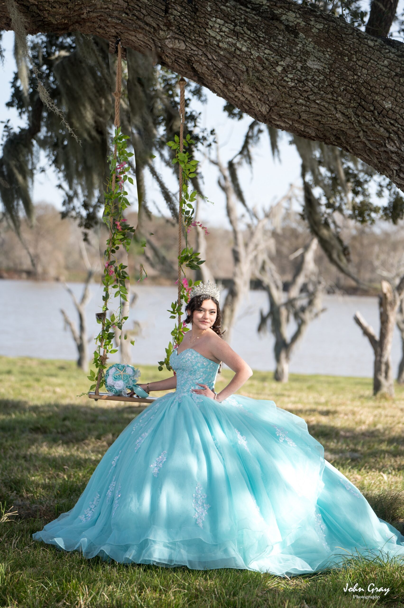 Quince girl standing next to a swing hanging from a 200+ year old oak tree with spanish moss gangling from the branches in front of a lake
